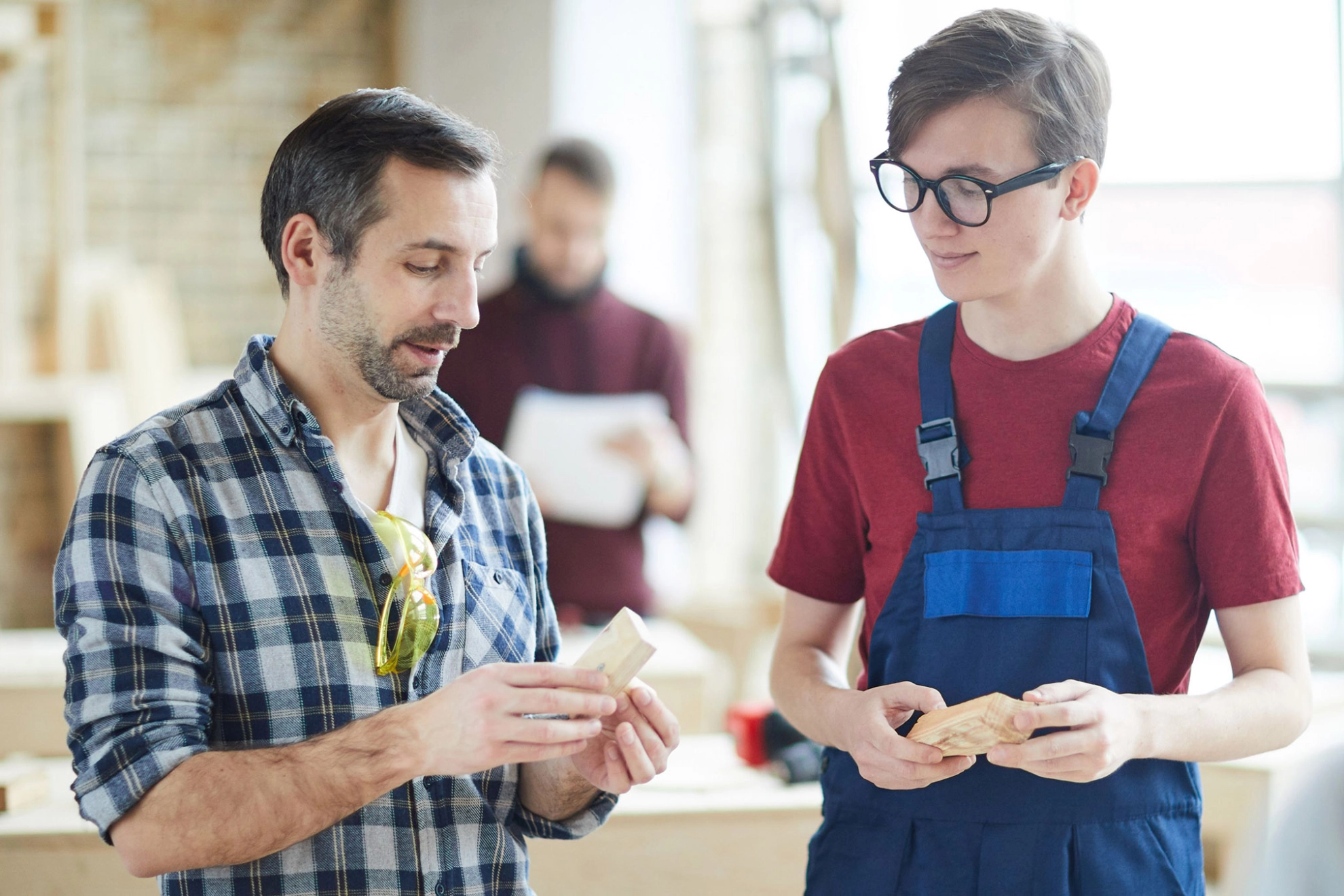 Auszubildender und Meister im Gespräch in einer Schreinerwerkstatt