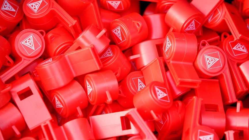 Viele rote Trillerpfeifen mit dem Logo der IG Metall.